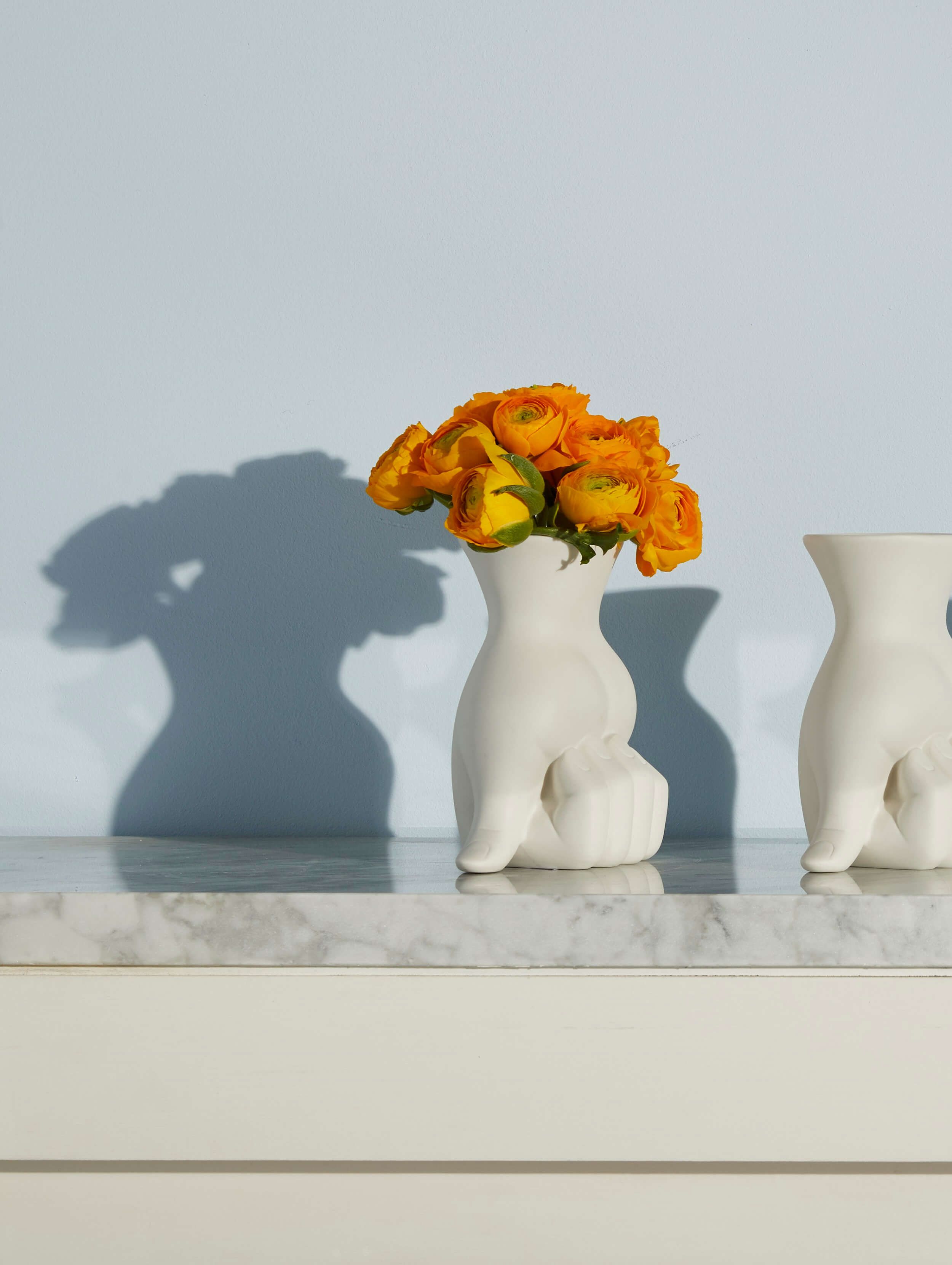 Zwei weisse Jonathan Adler Vasen mit orangen Blumen